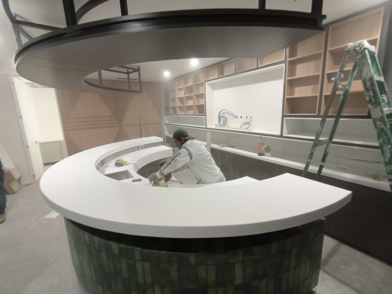 Barra circular de Corian blanco instalada sobre un mueble de azulejo verde