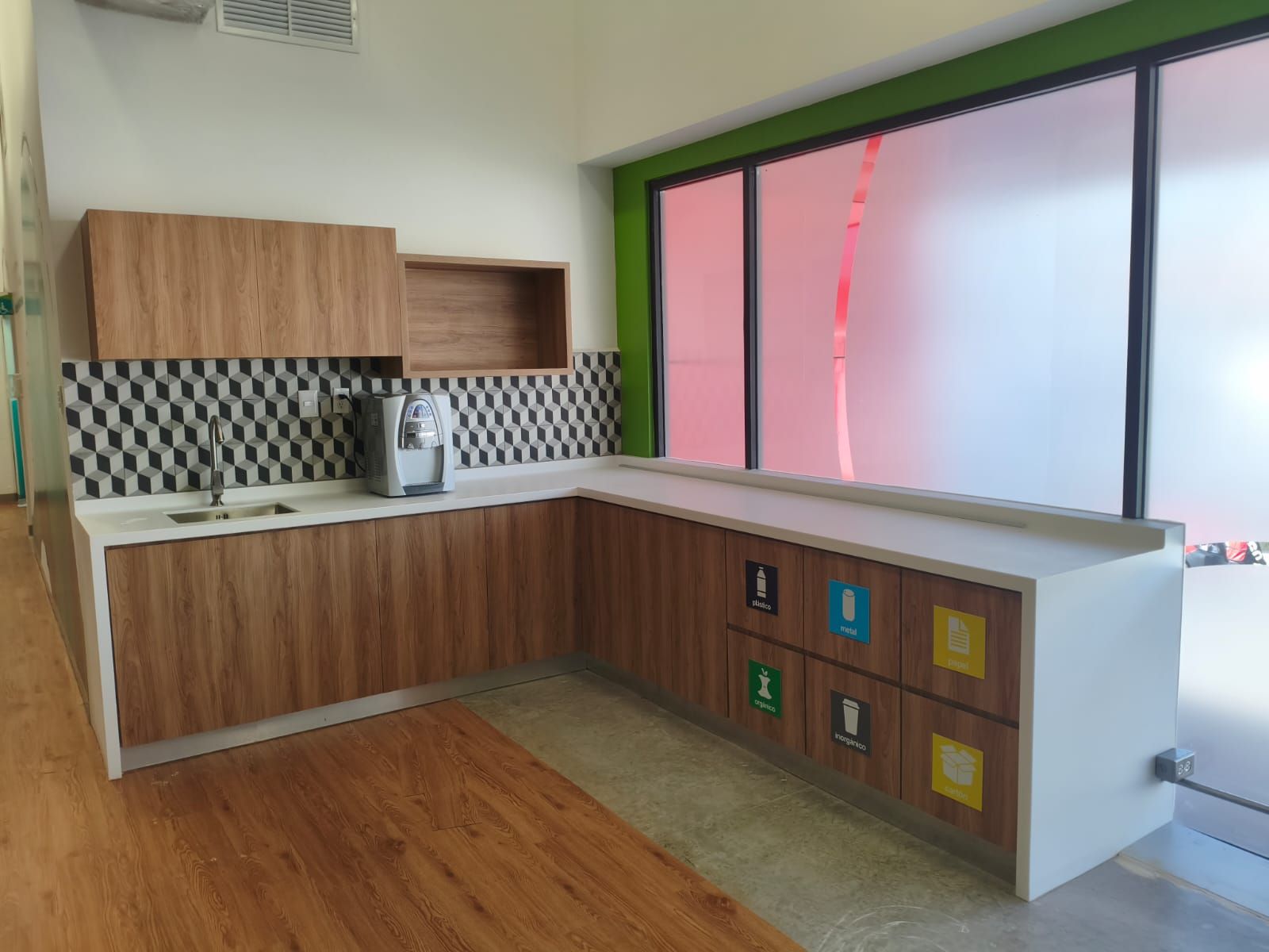 Cocineta con cubierta blanca, tarja integrada y muebles de madera junto a un ventanal