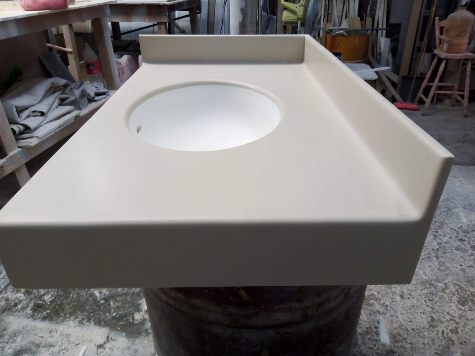 Cubierta de baño de Corian color arena con lavabo circular integrado y respaldo