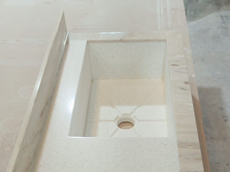 Lavabo rectangular integrado con respaldo lateral en una cubierta de tono claro