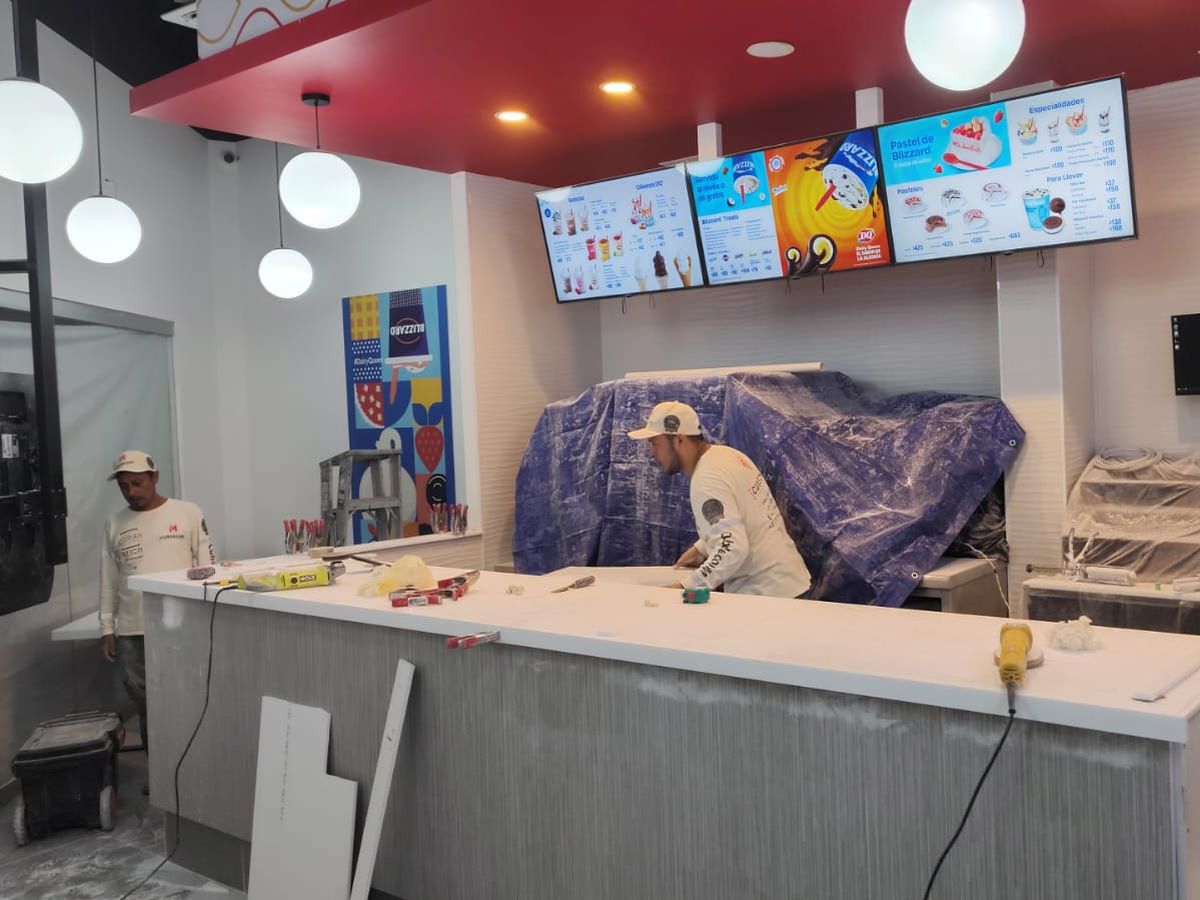 Instaladores trabajando sobre un mostrador blanco en un local en obra