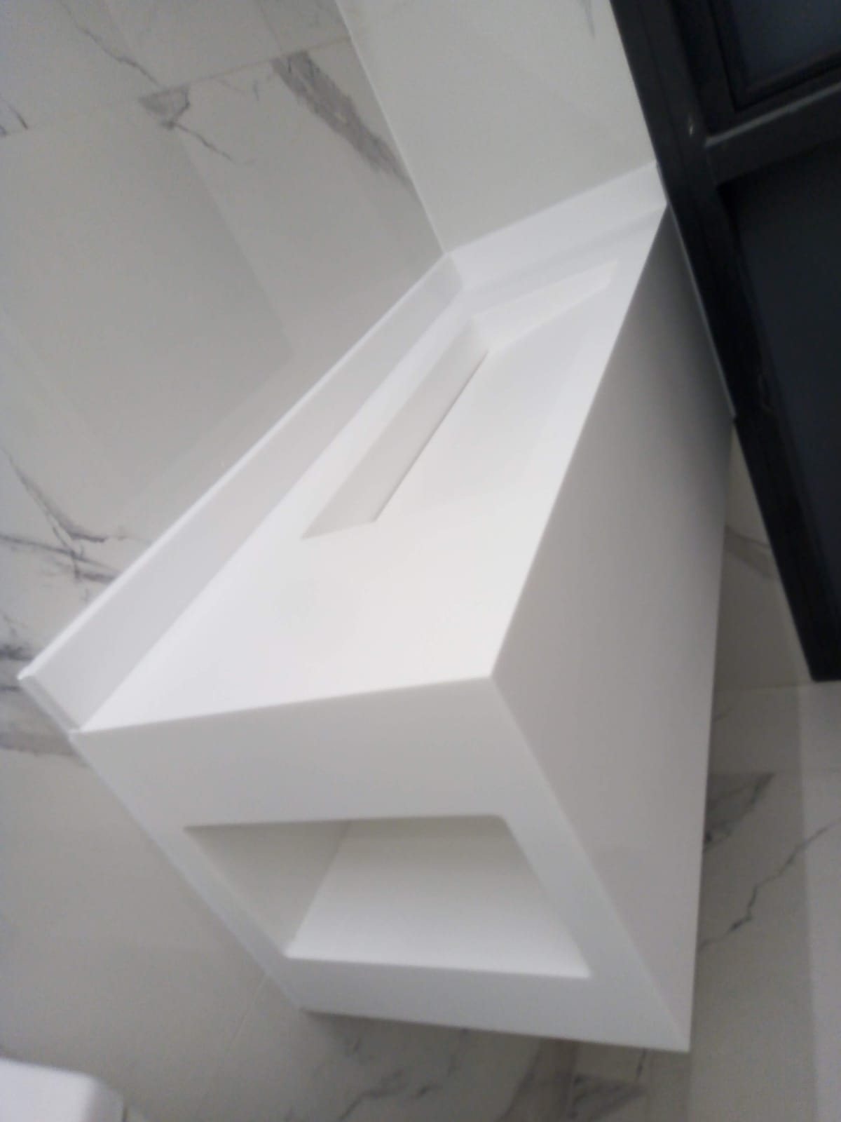 Mueble de baño de Corian blanco con lavabo integrado y nicho