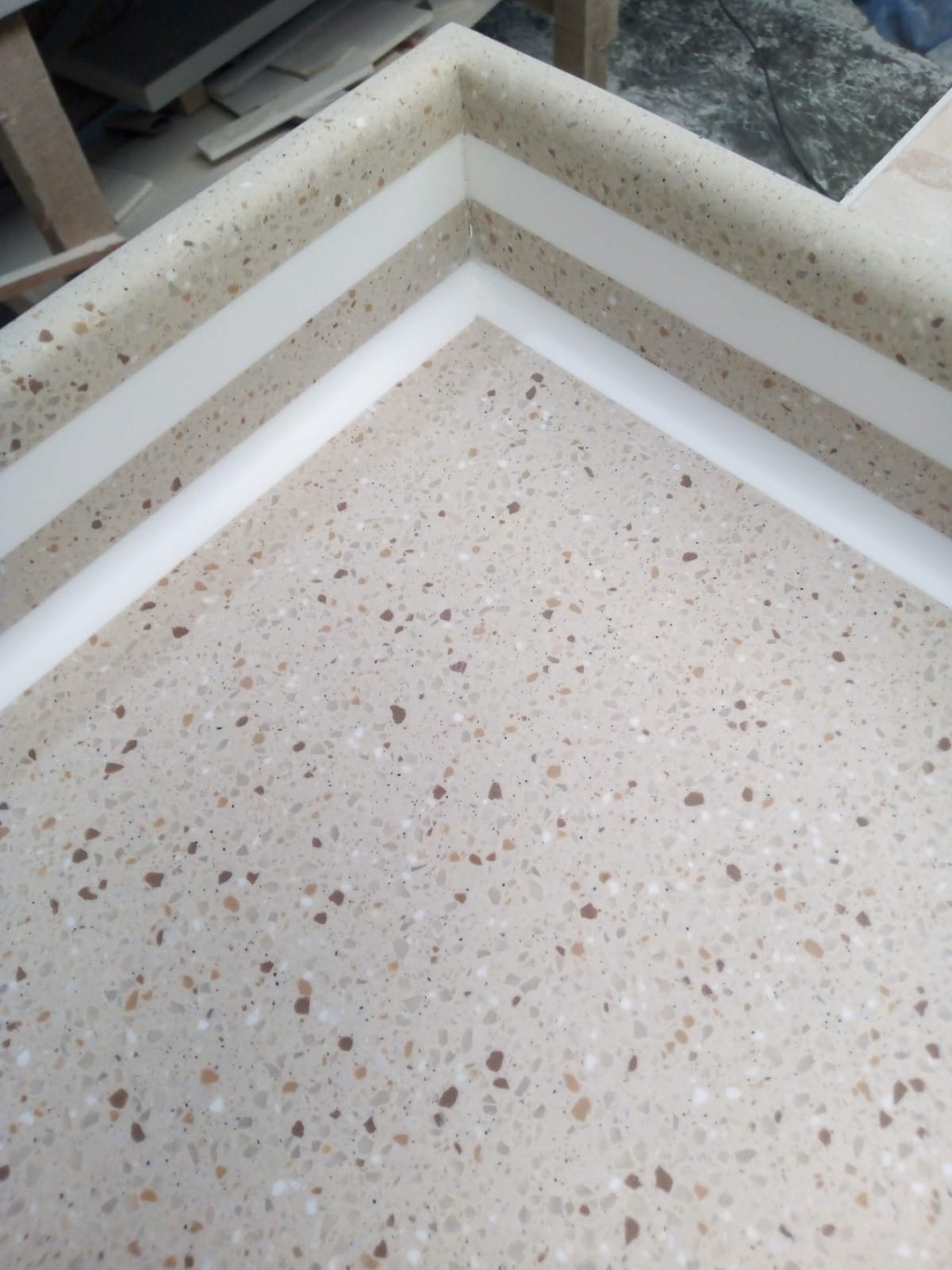 Detalle de cubierta de Corian tipo terrazo con partículas de color y perfil blanco